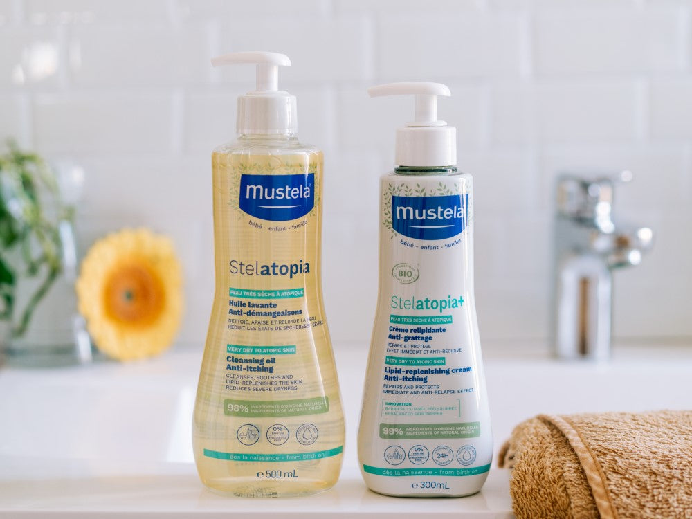 Mustela Stelatopia, cleansing oil and Stelatopia+ cream pump bottles by a sink