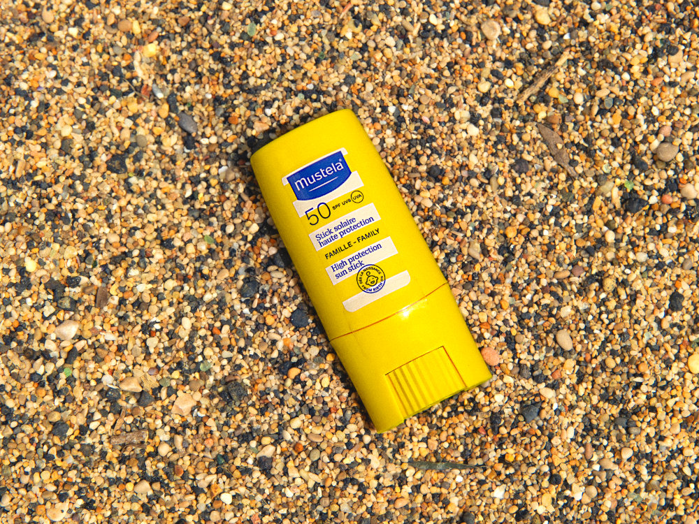 Mustela Sun Stick, stick lying on the sand