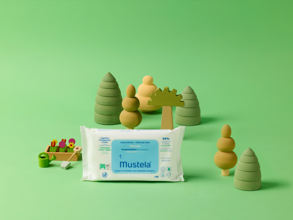 Mustela Water Cleansing Wipes, pack among wooden toy trees on a green background