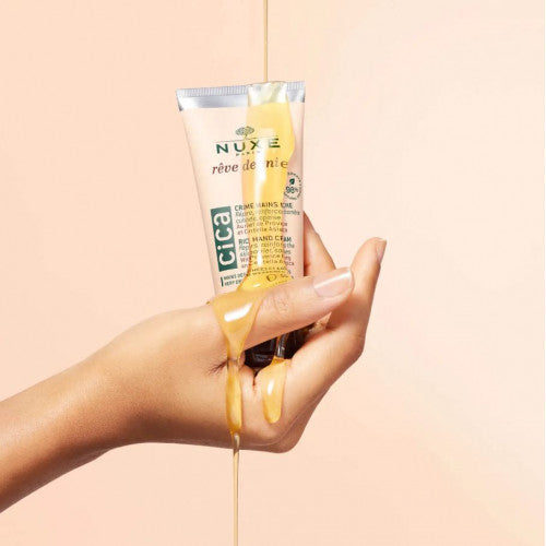 NUXE Honey Hand Cream, honey pouring over the tube in a hand