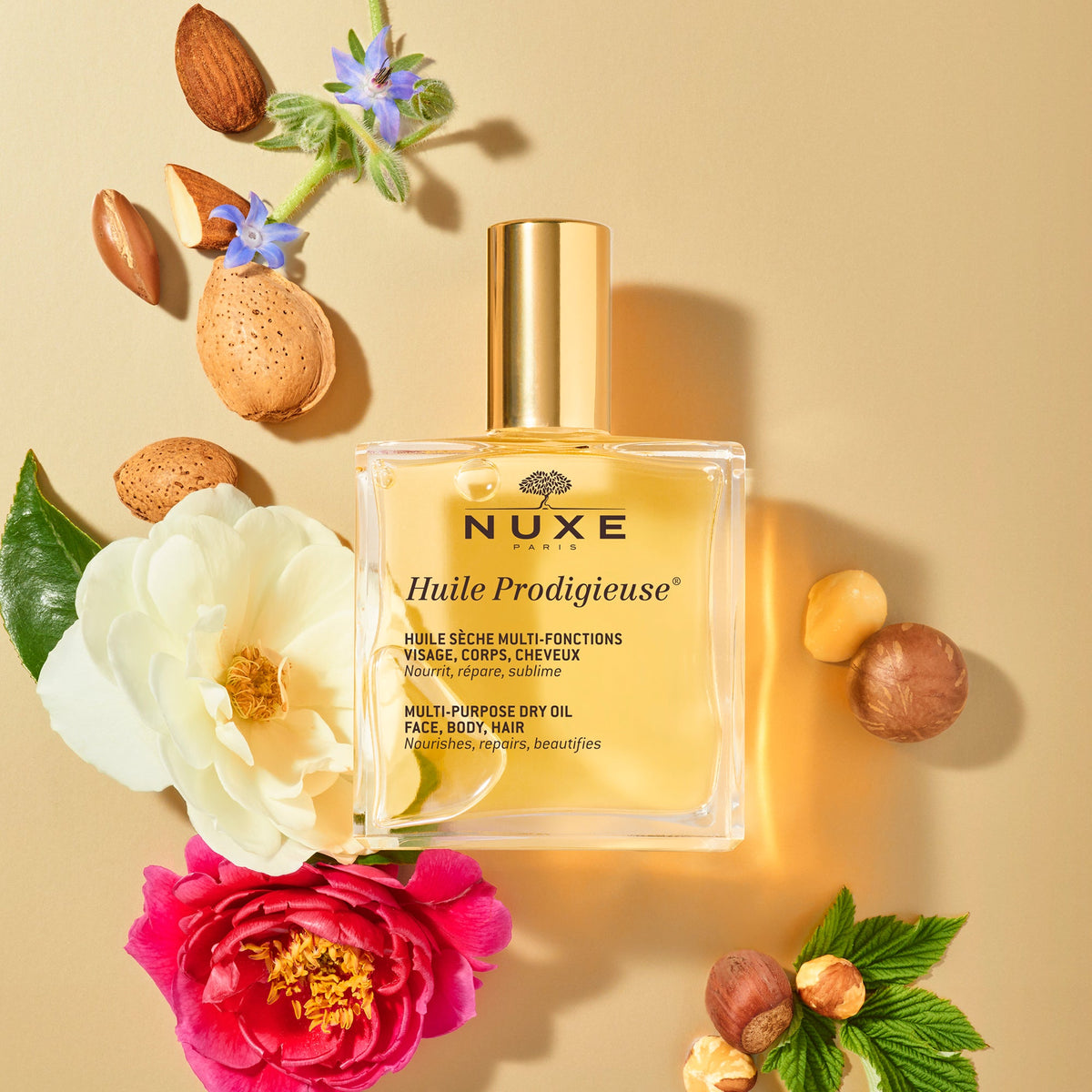 NUXE Huile Prodigieuse, classic dry oil bottle among flowers, almonds and hazelnuts