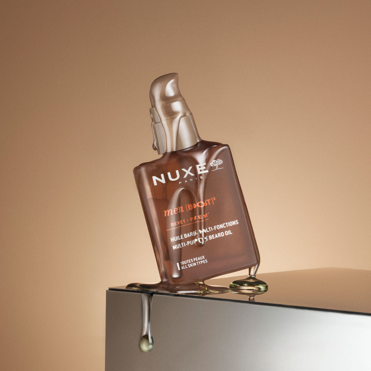 NUXE Men Boost, pump bottle tilted on a ledge with dripping oil
