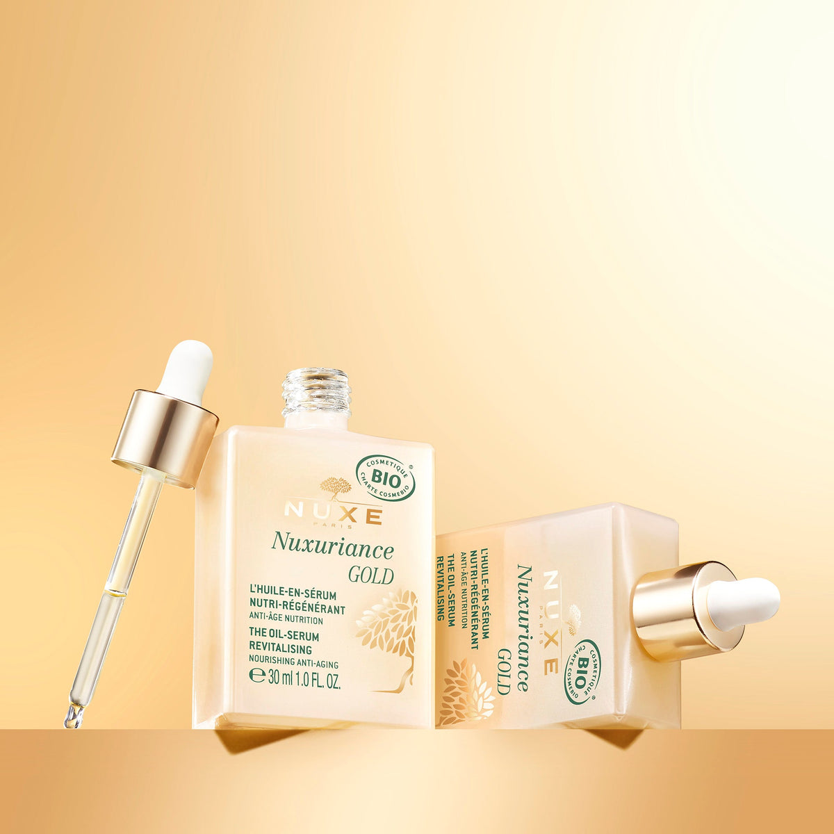 NUXE NUXURIANCE GOLD, open bottle, box and droppers on a golden background