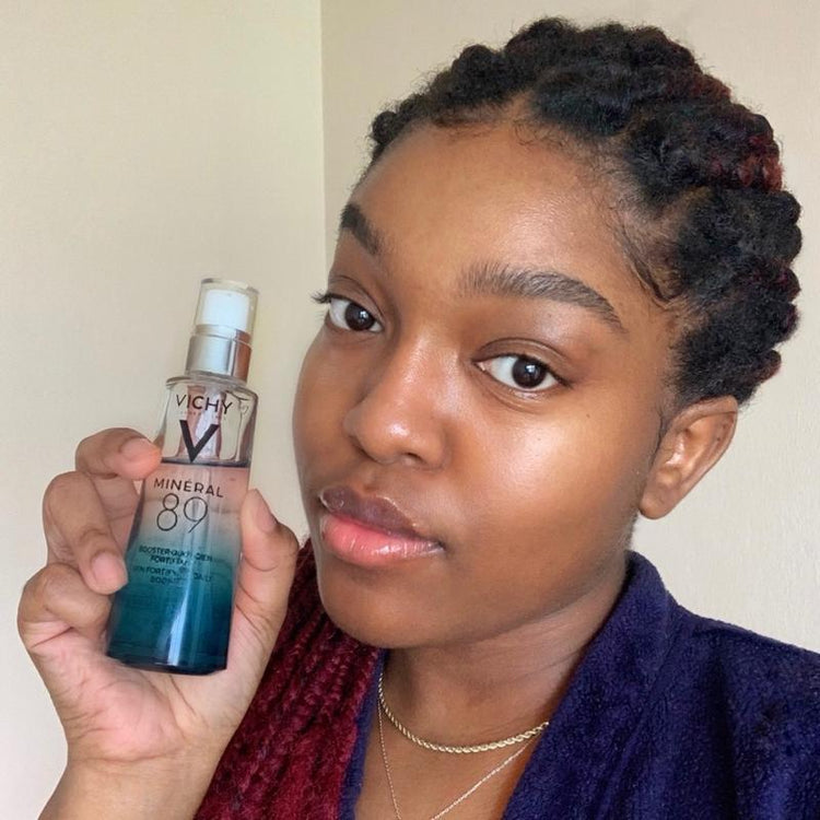 Person holding a Vichy mineral water bottle against a plain background