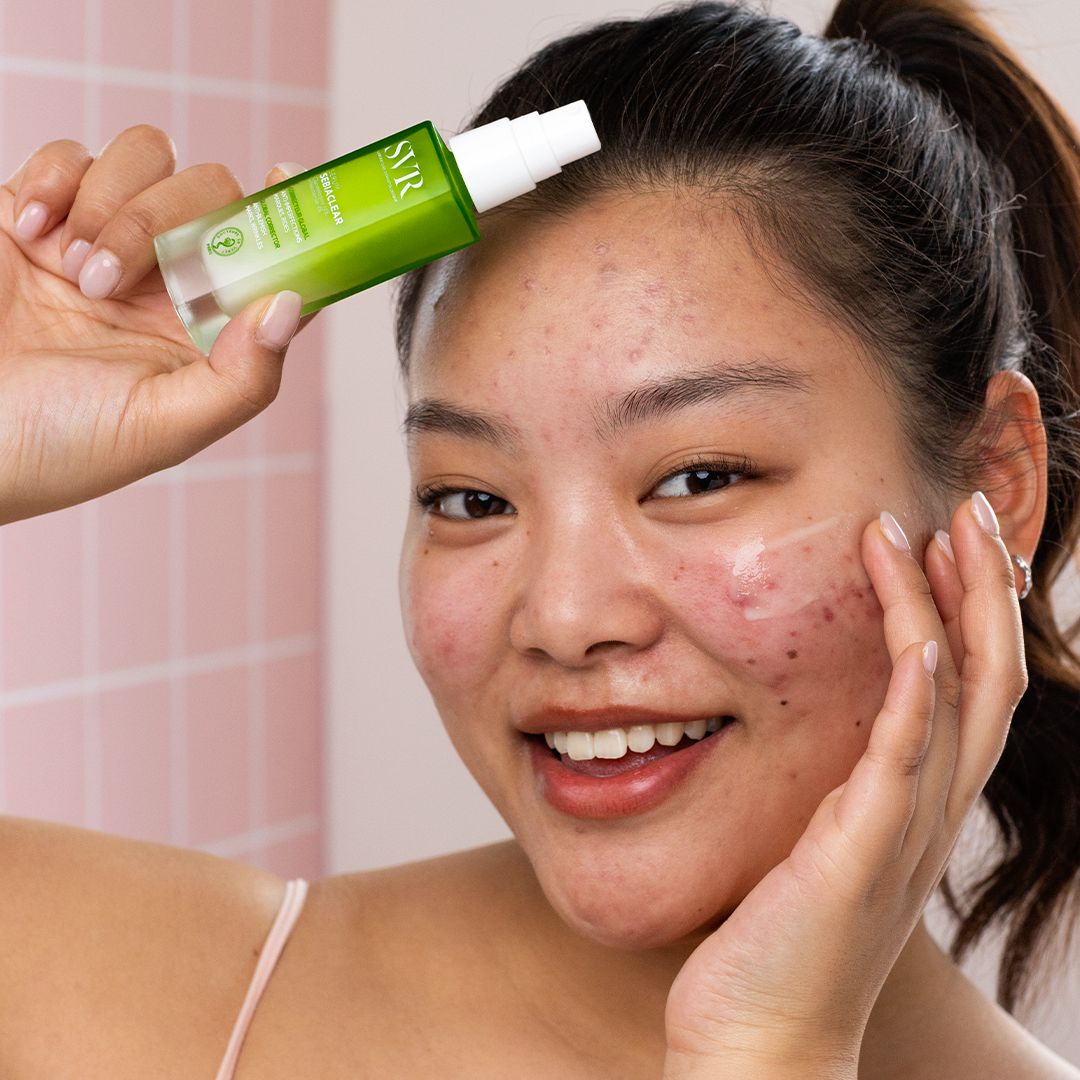 SVR Sebiaclear, smiling woman holding the pump bottle with serum on her cheek