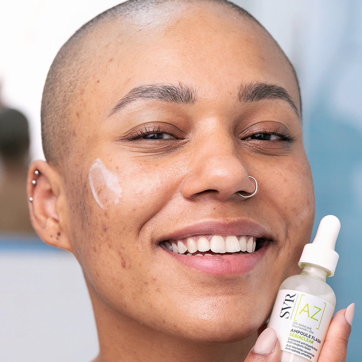 SVR SEBIACLEAR, smiling woman with the serum on her cheek, holding the bottle