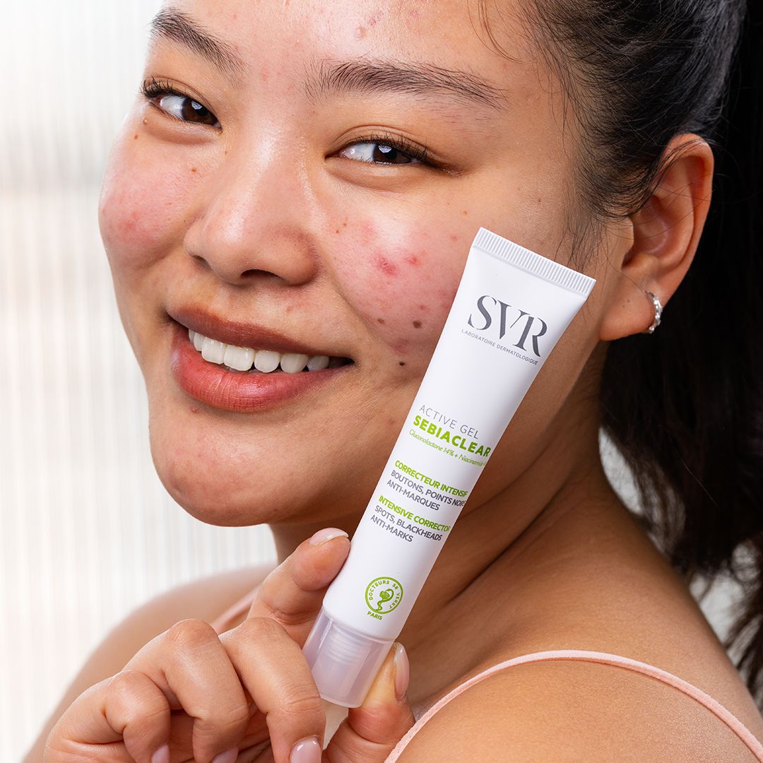 SVR Sebiaclear, smiling woman holding the tube to her cheek