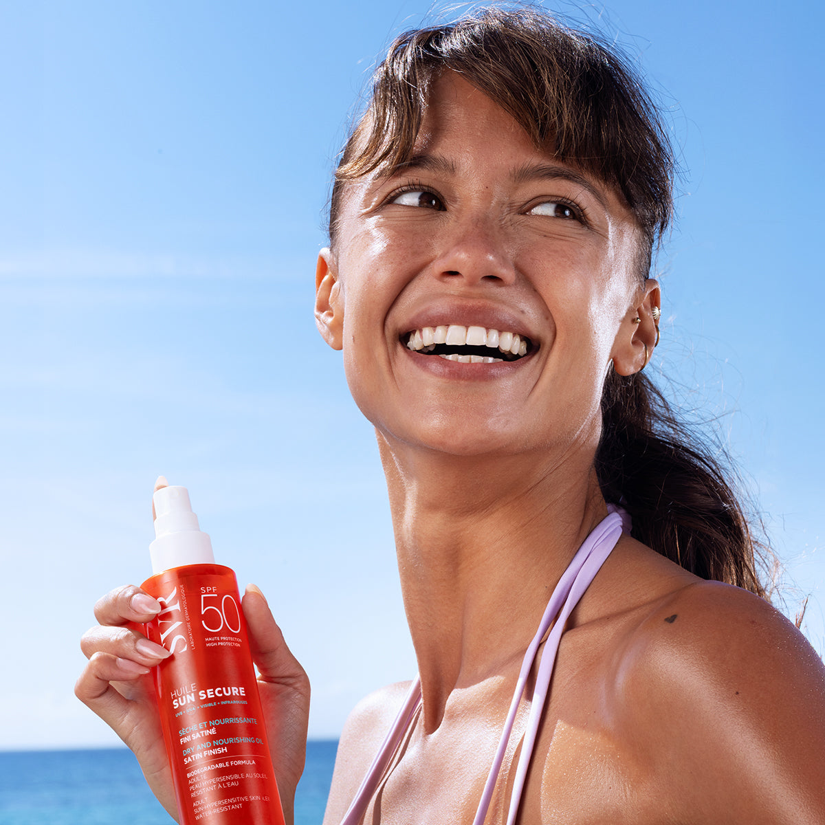 SVR Sun Secure, smiling woman at the beach holding the spray bottle