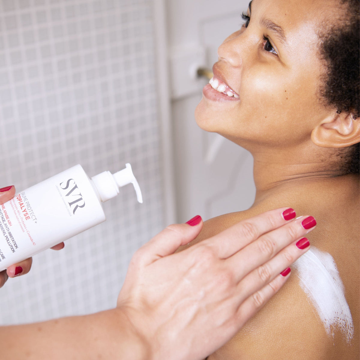 SVR Topialyse, smiling woman applying balm to her shoulder