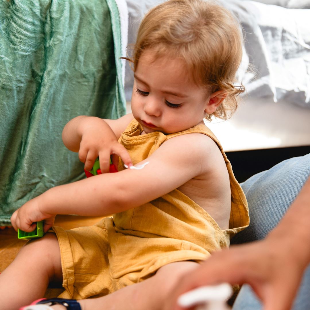 Topicrem DA, toddler applying the balm to the arm