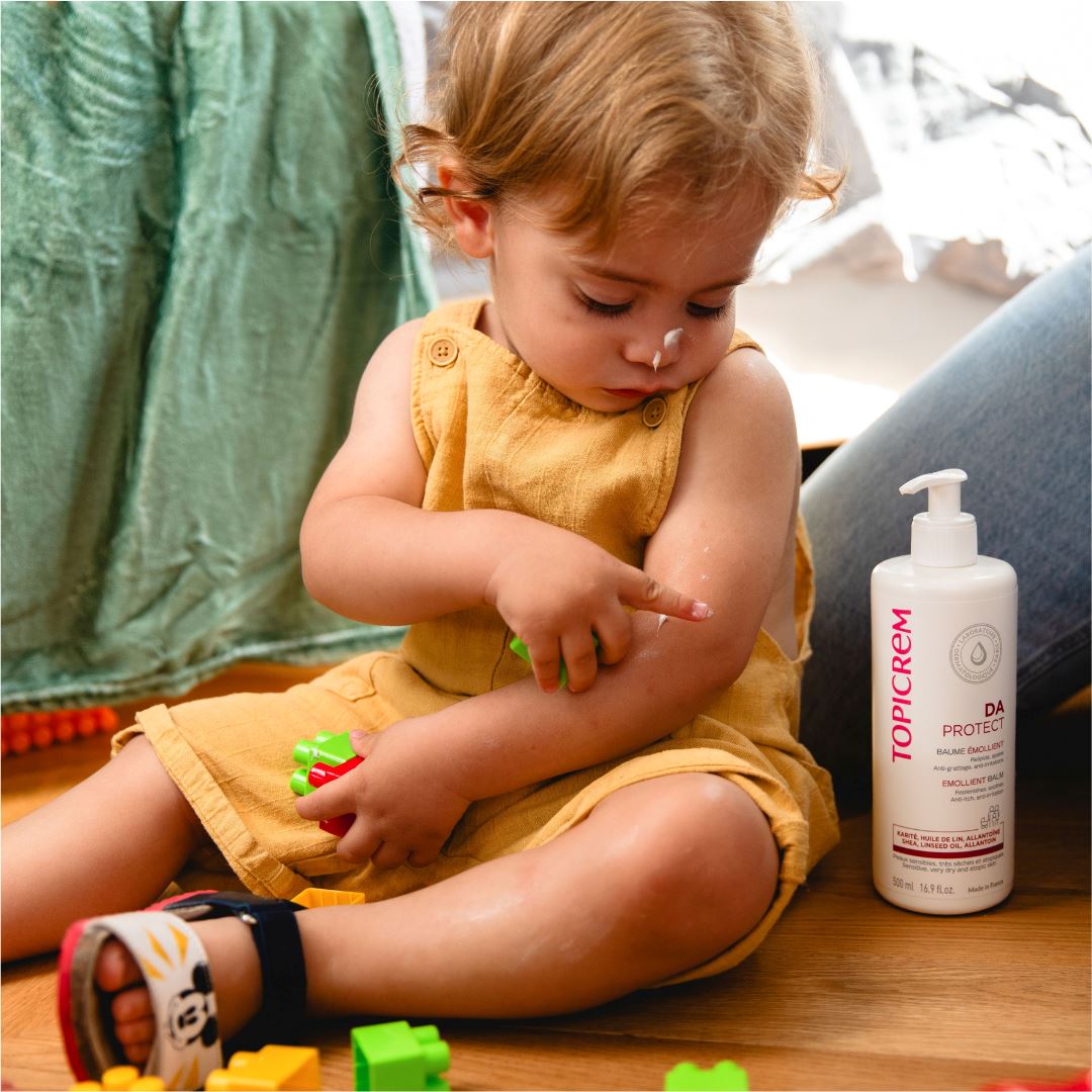 Topicrem DA, toddler with balm on the arm beside the pump bottle