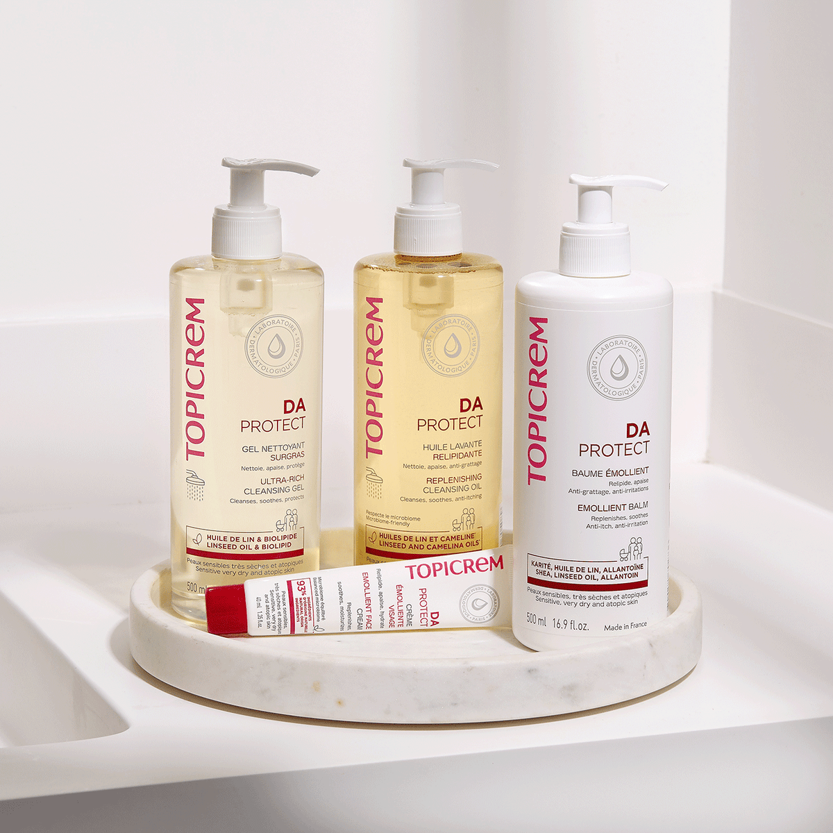 Topicrem DA, three pump bottles and a tube on a round tray