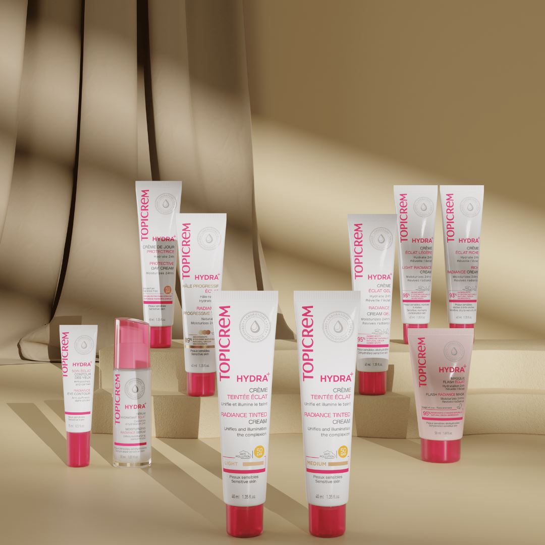 Topicrem HYDRA+, range of tubes and a serum bottle on beige steps