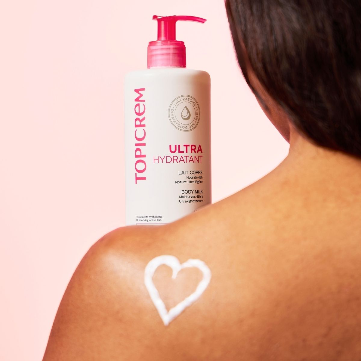 Topicrem Ultra Hydrating, pump bottle on a shoulder with a heart of milk