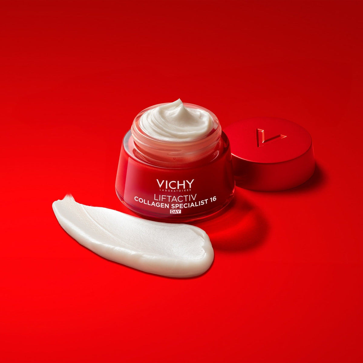 Vichy Liftactiv Collagen Specialist, open jar, lid and cream swatch on a red background