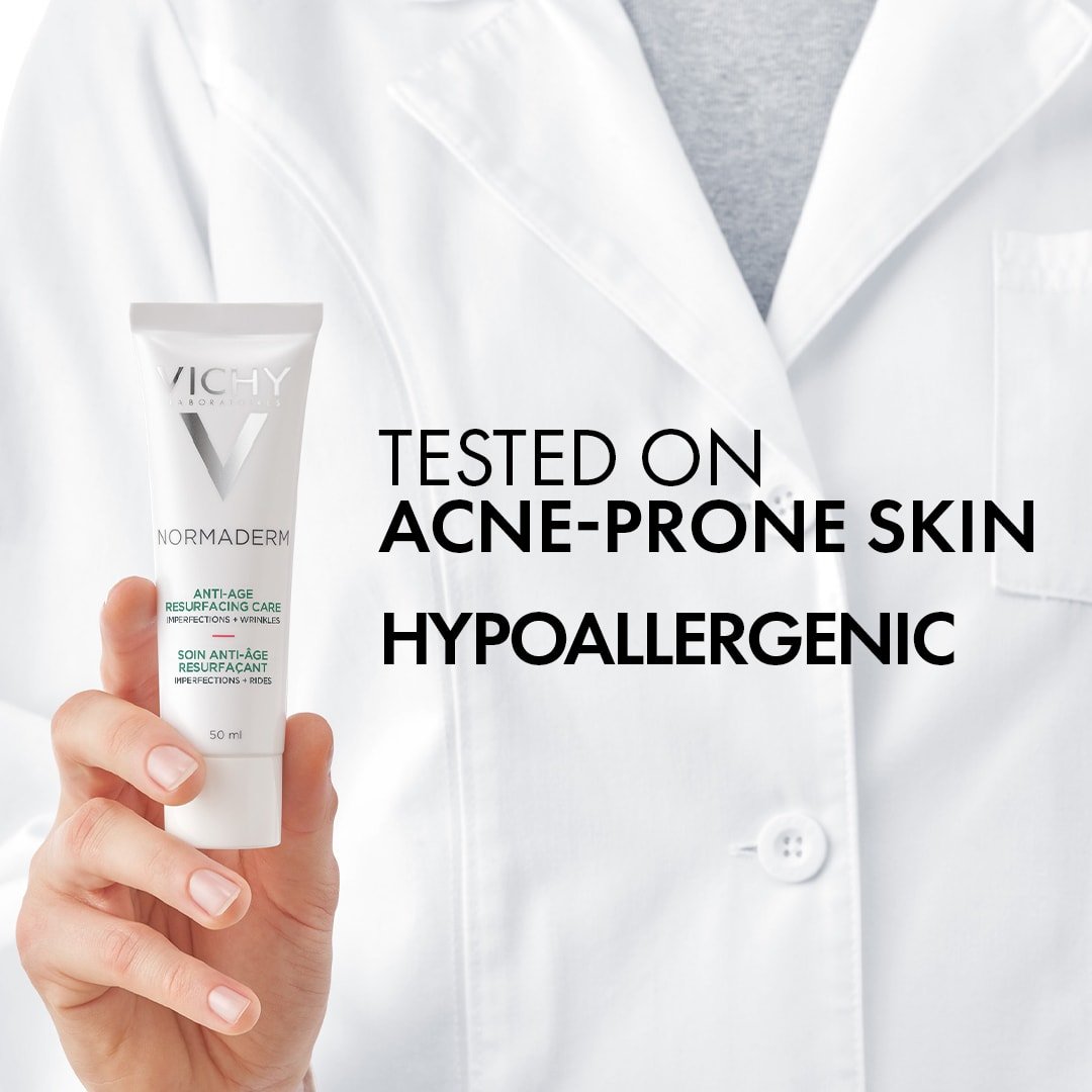 Vichy Normaderm, hand holding the tube against a white lab coat