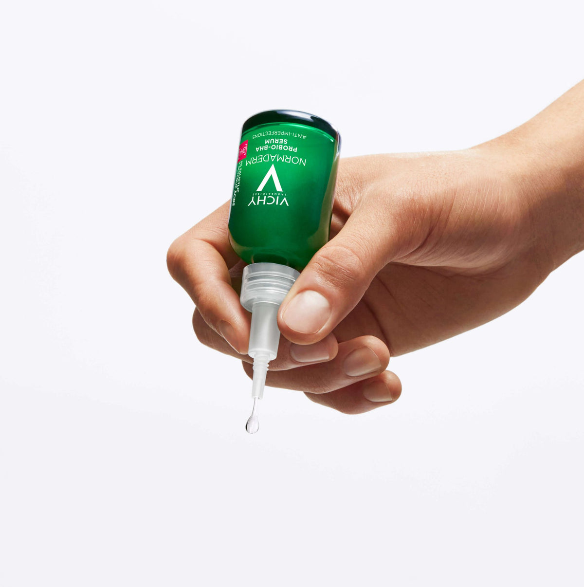 Vichy Normaderm, hand holding the bottle upside down with a falling drop