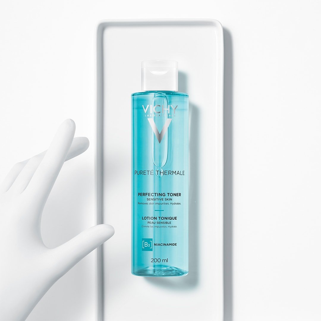 Vichy Pureté Thermale 200ml, bottle on a white tray beside a sculpted hand