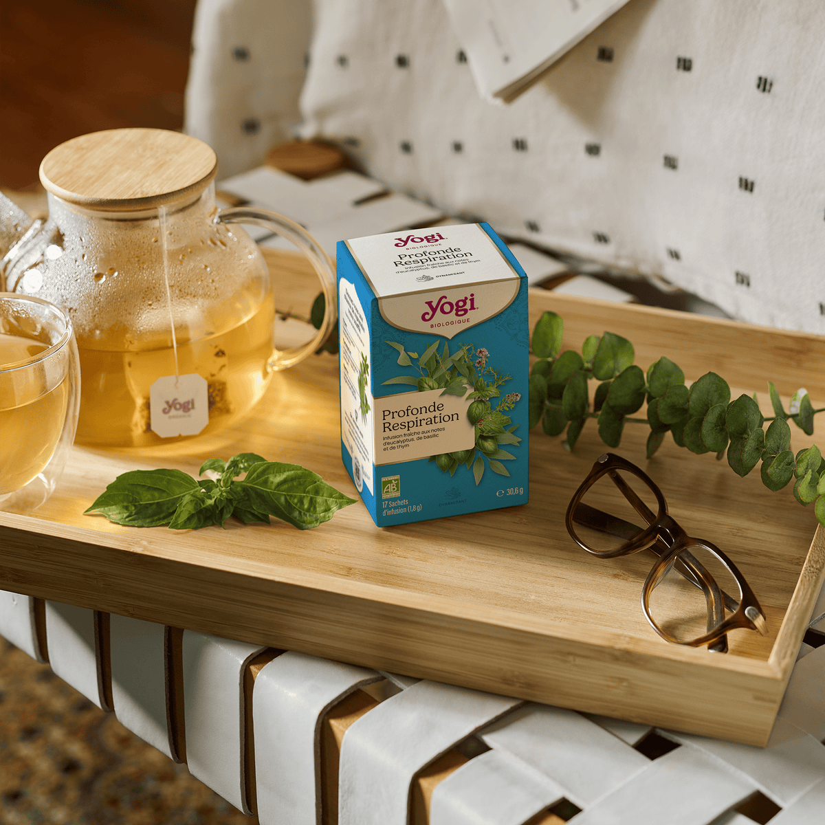 Yogi Tea Breathe Deep, box on a bamboo tray with a glass teapot, basil and eucalyptus
