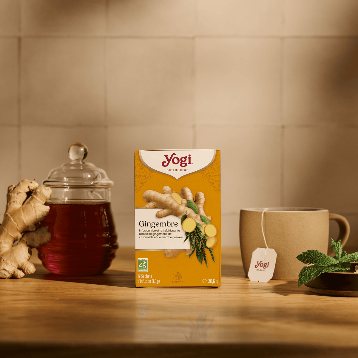 Yogi Tea Ginger, box on a wooden counter with ginger root, a jar of infusion and a mug